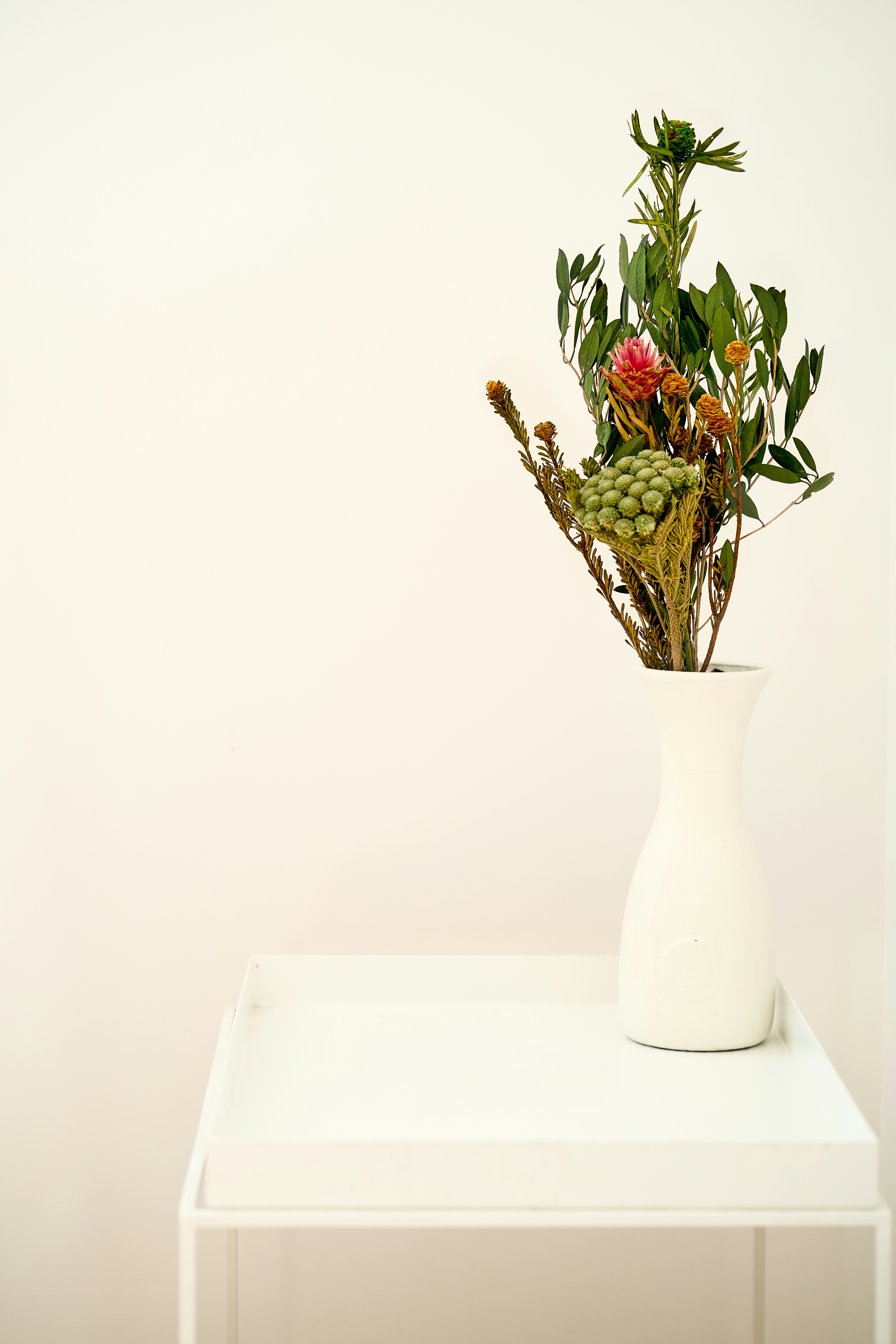 red roses in white ceramic vase on white table